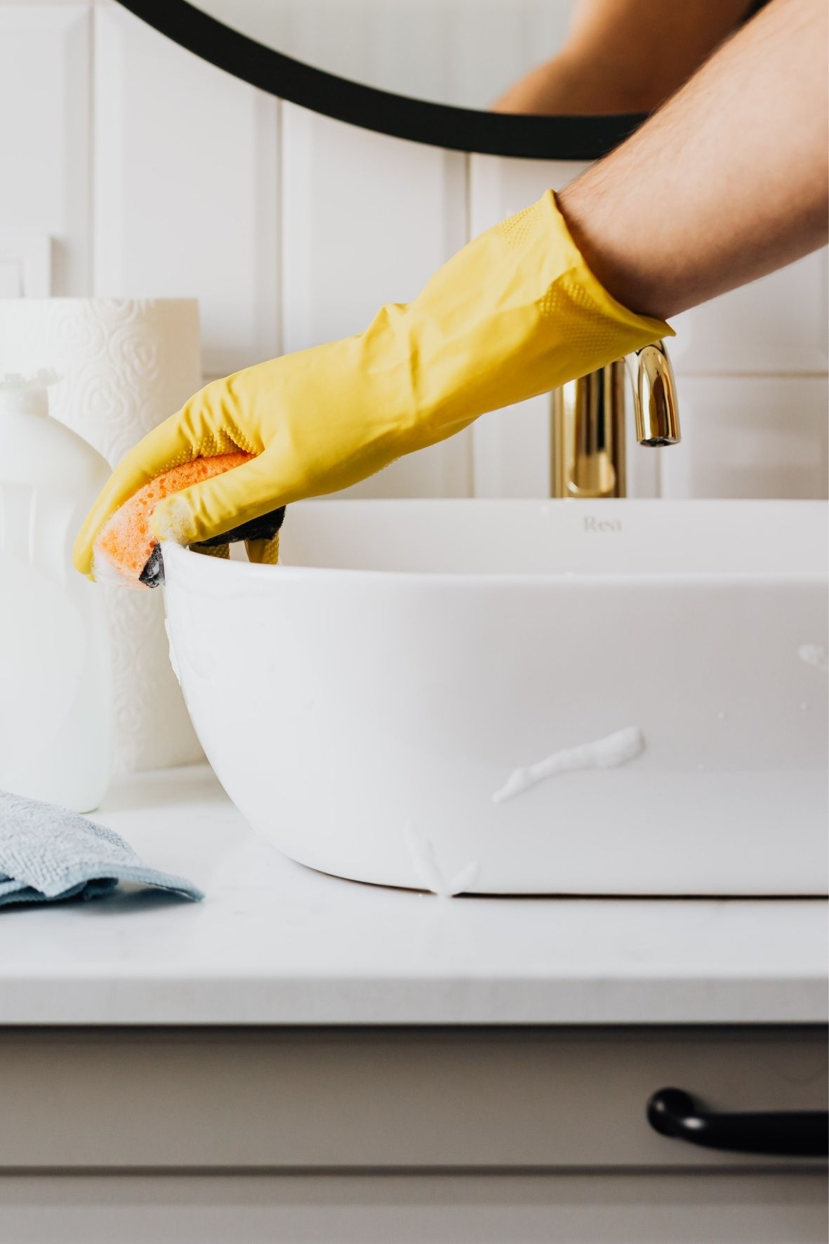 Main gantée nettoyant un lavabo dans un espace sanitaire moderne et propre  à Saint-Rémi